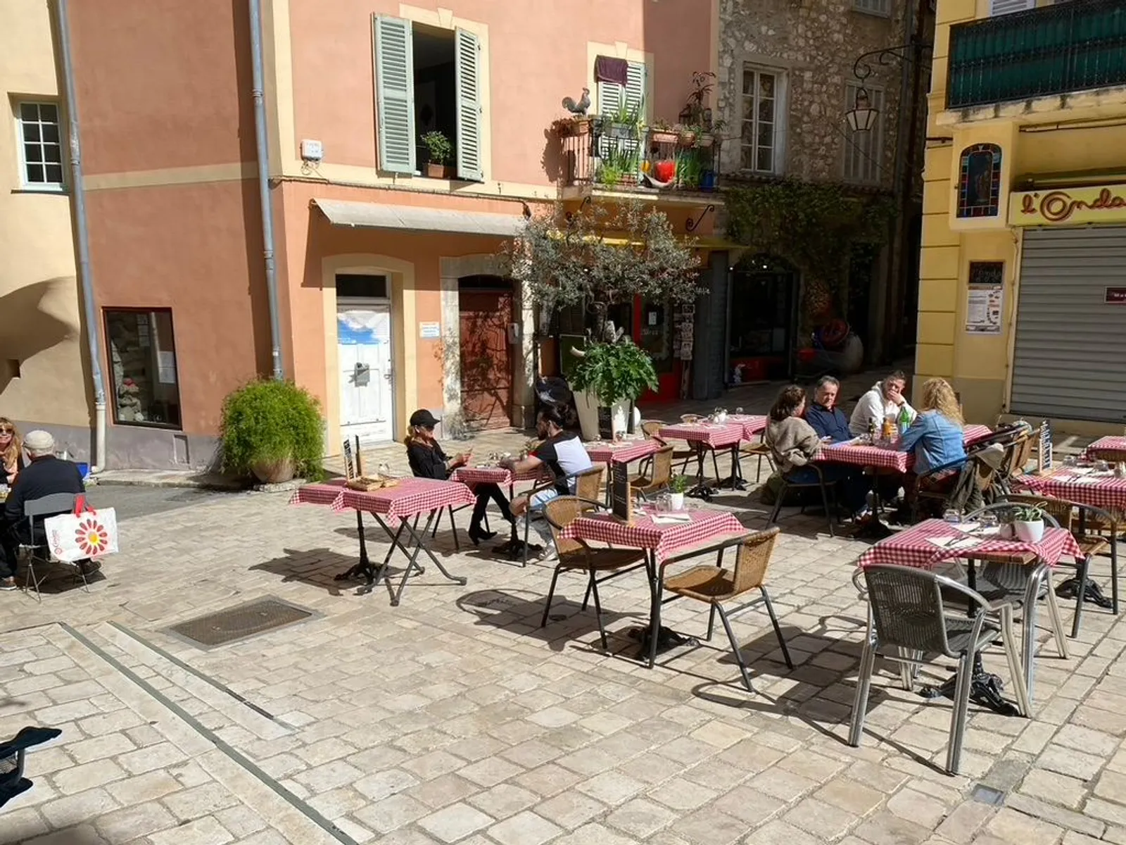 Visitors enjoying the sunny square in front of Galerie Joie De Vivre